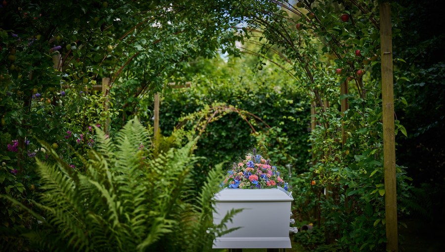 Hvid kiste med blomster i en naturskøn have – Kim Bondo Bedemand